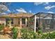 The landscaped backyard features a screened-in lanai, mature plants, and a cozy outdoor seating area at 2359 Emerald Lake Dr, Sun City Center, FL 33573