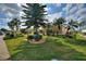 Well-manicured front yard with lush landscaping, mature trees, and a variety of plants, with a partial view of the house at 2359 Emerald Lake Dr, Sun City Center, FL 33573