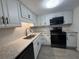 Renovated kitchen features white cabinetry, dark hardware, stainless sink, black appliances, and sleek counters at 2459 Columbia Dr # 39, Clearwater, FL 33763