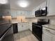 A beautifully updated kitchen featuring white cabinetry, granite countertops, and modern black appliances at 2459 Columbia Dr # 39, Clearwater, FL 33763