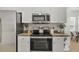 Close up of modern kitchen featuring stainless steel appliances, white cabinets and tile floor at 2537 Stanhope Dr, New Port Richey, FL 34655
