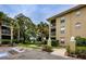 Exterior shot of condo building nestled among mature trees and verdant landscaping with pond views at 2690 Coral Landings Blvd # 122, Palm Harbor, FL 34684