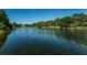 Scenic lake view showcasing lush green trees along the banks and a clear blue sky above the water at 2690 Coral Landings Blvd # 122, Palm Harbor, FL 34684