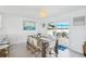 Light-filled dining area features a rustic wood table, wicker chairs, modern chandelier, and sliding door to outdoor patio at 311 22Nd St, Belleair Beach, FL 33786