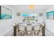 Charming dining area features a rustic table, wicker chairs, modern chandelier, and view to a pool and waterway at 311 22Nd St, Belleair Beach, FL 33786