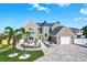 Elegant two-story home showcasing a unique architectural design, well-kept lawn, and circular paver driveway at 311 22Nd St, Belleair Beach, FL 33786