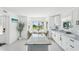 Bright kitchen with white cabinets, a marble island, and a view through the windows at 311 22Nd St, Belleair Beach, FL 33786
