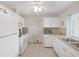 Bright kitchen boasts white appliances, tile flooring, and door access to the outside at 3515 100Th N Ter, Pinellas Park, FL 33782