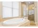 Bright bathroom featuring a soaking tub and glass-enclosed shower with beige tile at 3814 W Sevilla St, Tampa, FL 33629