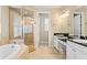 Bright bathroom with double vanity, black countertops, soaking tub, and glass-enclosed shower at 3814 W Sevilla St, Tampa, FL 33629