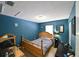 Bedroom with blue walls, a wooden bed, desk area, and a window providing natural lighting at 4015 My Lady Ln # 7, Land O Lakes, FL 34638