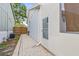 The home's exterior side with door to pool area, brick walkway, and house utilities at 417 Manor Blvd, Palm Harbor, FL 34683