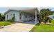 Light blue home with white trim, well-manicured lawn, and a covered carport at 427 Pelican S Dr, Oldsmar, FL 34677