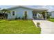 Charming light blue home with white trim, well-manicured lawn, and a covered carport at 427 Pelican S Dr, Oldsmar, FL 34677