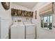 Bright laundry room featuring a white washer and dryer, floral valance, and natural light at 427 Pelican S Dr, Oldsmar, FL 34677