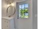 Bathroom features modern fixtures, round mirror and glass-paneled exterior door for ample light at 4518 Helena Ne St, St Petersburg, FL 33703