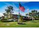 Lake Overlook Condominiums entrance features American flag, brick sign, and lush landscaping under a bright blue sky at 4580 Overlook Ne Dr # 191, St Petersburg, FL 33703