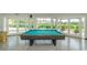 Bright game room featuring a pool table, terrazzo floors, and views of the lush outdoor landscape through large windows and glass doors at 4580 Overlook Ne Dr # 191, St Petersburg, FL 33703