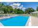 Community pool is surrounded by a white fence and lounge chairs under a partly cloudy, bright blue sky at 4580 Overlook Ne Dr # 191, St Petersburg, FL 33703