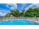 Community pool has multiple chairs under umbrellas near mature trees and bushes under a bright blue sky at 4580 Overlook Ne Dr # 191, St Petersburg, FL 33703