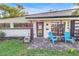 Charming home with two light blue chairs outside the front door and black trimmed windows at 489 W Davis Blvd, Tampa, FL 33606
