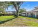 Lovely front yard with mature trees, lawn, landscaping, and charming blue chairs on the home's front porch at 489 W Davis Blvd, Tampa, FL 33606
