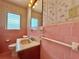 Vintage-style bathroom featuring pink tile, a classic vanity, and a window for natural light, very retro! at 4906 N Arrawana Ave, Tampa, FL 33614