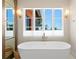 Bright bathroom with a modern soaking tub, large window, and decorative wall sconces at 501 Brightwaters Ne Blvd, St Petersburg, FL 33704