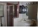 A bathroom featuring a glass-door shower, vanity sink, mirrored wall, and dark wooden shelving at 5581 Greyston St, Palm Harbor, FL 34685