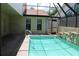 A sparkling swimming pool with a screen enclosure, stone accents, and patio area at 5581 Greyston St, Palm Harbor, FL 34685