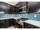 Kitchen with stainless steel appliances, dark cabinetry, white countertops and light blue subway tile backsplash at 575 53Rd N Ave, St Petersburg, FL 33703