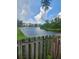 Backyard with lake, bordered by a wooden fence, with a view of neighborhood homes in the distance at 5806 Tulip Flower Dr, Riverview, FL 33578