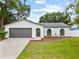 Charming single-story home with a well-manicured lawn, gray garage door, and beautiful landscaping at 6204 Walsh Ln, Tampa, FL 33625