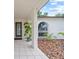 Covered front porch with tiled floor and decorative glass front door, surrounded by lush landscaping at 6204 Walsh Ln, Tampa, FL 33625