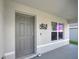 Close up of the front door with gray coloring, a doorbell, a window, and an ornate wall hanging at 7737 Rosewood Garden Loop, Tampa, FL 33637