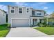 View of the two-story home with a manicured lawn, neutral stucco, attached garage, and an inviting covered entryway at 7737 Rosewood Garden Loop, Tampa, FL 33637