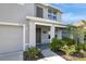 View of the front porch with supporting columns, muted gray door, desert-friendly landscaping, and a two-car garage at 7737 Rosewood Garden Loop, Tampa, FL 33637