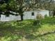 White home with lawn and mature trees for shade on a bright sunny day at 9053 Bourbon St, New Port Richey, FL 34654