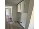 Hallway with overhead cabinets and views into carpeted bedroom and adjacent doorway at 9053 Bourbon St, New Port Richey, FL 34654