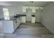 Bright kitchen featuring white cabinets, granite countertops, and modern gray wood flooring at 9053 Bourbon St, New Port Richey, FL 34654