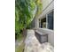 Exterior shot of paved walkway, window, and exterior storage unit alongside a wall of green tropical landscaping at 10675 Park Place Dr, Largo, FL 33778