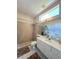 Bathroom featuring a shower with tile surround, a single vanity, and a large window for natural light at 10675 Park Place Dr, Largo, FL 33778