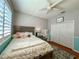 Cozy bedroom featuring plantation shutters, a ceiling fan, hardwood floors, and a built-in vanity area at 10675 Park Place Dr, Largo, FL 33778