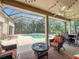 Charming screened patio with comfortable seating, a fan and string lights overlooks the backyard pool and lush greenery at 10675 Park Place Dr, Largo, FL 33778