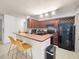 This open kitchen features wood cabinets, a breakfast bar with seating, and modern appliances at 12912 Arbor Isle Dr # 202, Temple Terrace, FL 33637