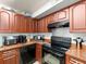 This kitchen features wood cabinets, granite countertops, and black appliances at 12912 Arbor Isle Dr # 202, Temple Terrace, FL 33637