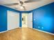 Vibrant blue bedroom with blonde floors, ceiling fan, and ensuite bathroom at 1319 Dew Bloom Rd, Valrico, FL 33594