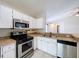 Well-equipped kitchen features stainless steel appliances and tiled countertops with white cabinets at 1319 Dew Bloom Rd, Valrico, FL 33594