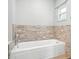 Clean white bathtub with updated, neutral-toned tile surround and a window for natural light at 22422 Stillwood Dr, Land O Lakes, FL 34639