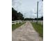 Gravel driveway leading to a gated entrance surrounded by lush greenery and a white fence at 22422 Stillwood Dr, Land O Lakes, FL 34639
